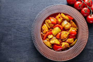 Chicken jalfrezi Indian traditional fried spicy curry chilli meat and vegetables healthy dietetic food in clay dish on vintage table background.