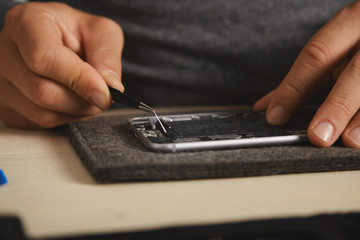 Using pincher tool to remove battery glue from opened smartphone to replace and fix it with new one