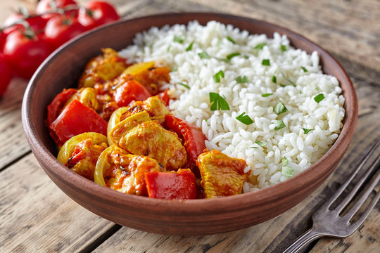Chicken jalfrezi healthy traditional Indian curry spicy fried meat with vegetables and basmati rice food in clay plate on vintage table background
