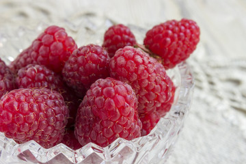 Sweet raspberries on plate on wooden table
