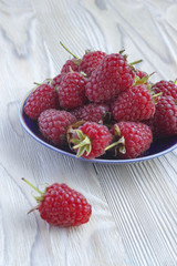 Sweet raspberries on plate on wooden table