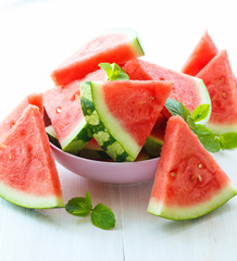 Triangular slices of watermelon with mint on white wooden backgr