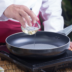 Chef pouring vegetable oil to the pan