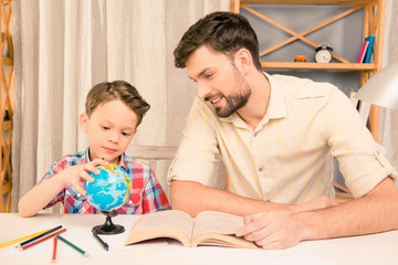Little boy studing geography with his dad at home