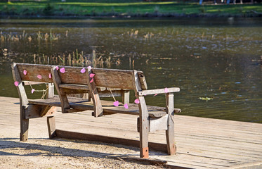 Rustic wooden park bench by the river draped in faded pink party decorations. Audley, Royal National Park, Australia