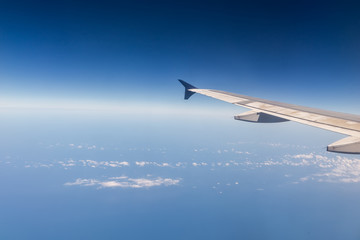 Wing of airplane flying above the clouds in the sky