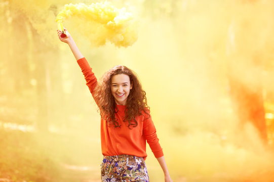 happy young woman having fun with colorful powder cloud