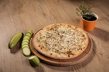 Pizza with chicken, four cheese and zucchini served on wooden pl