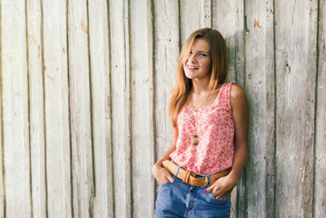 Fashion young blond woman in pink Tshirt over pale wooden background