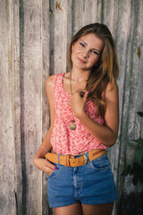 Naklejka premium Fashion young blond woman in pink Tshirt over pale wooden background
