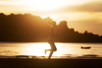Woman running on the beach at sunrise.