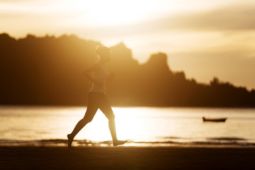 Woman running on the beach at sunrise.