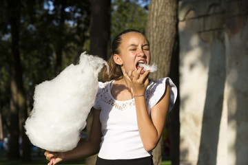 Girl eating cotton candy in a summer park