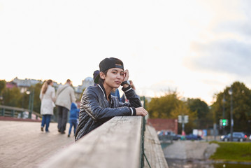 Girl or boy using phone to talk. Portrait of thinking and dreaming asian woman in autumn day. Hipster stay on wooden bridge in the city. Urban concept
