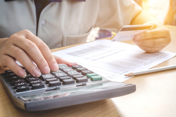 Close up hands holding a credit card and using calculator for on