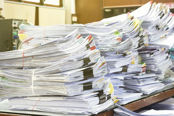 Pile of documents on desk stack up high waiting to be managed