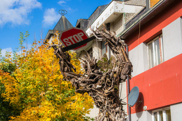 Statue is made with forest branches is standing with saw and stop sign that means Prohibition of...