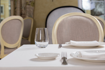Empty glasses and plates installed in the restaurant, the restaurant served table, white tablecloth and wine