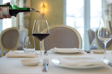 served table restaurant wine being poured into glass, white tablecloth, plates and cutlery