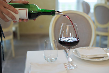 served table restaurant wine being poured into glass, white tablecloth, plates and cutlery