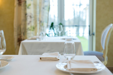 Empty glasses and plates installed in the restaurant, the restaurant served table, white tablecloth and wine