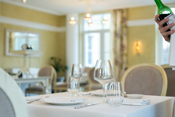 served table restaurant wine being poured into glass, white tablecloth, plates and cutlery