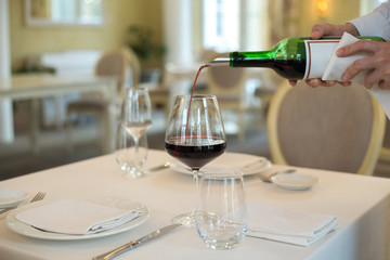 served table restaurant wine being poured into glass, white tablecloth, plates and cutlery
