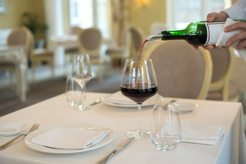 served table restaurant wine being poured into glass, white tablecloth, plates and cutlery
