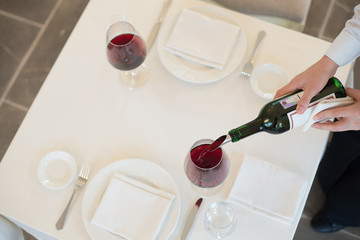 served table restaurant wine being poured into glass, white tablecloth, plates and cutlery