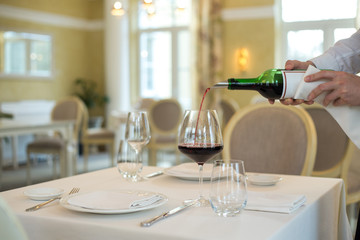 served table restaurant wine being poured into glass, white tablecloth, plates and cutlery