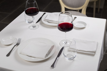 served table restaurant wine being poured into glass, white tablecloth, plates and cutlery