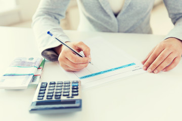 close up of hands counting money with calculator