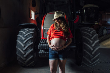 Obraz na płótnie Canvas pregnant next to a woman harvesting machine