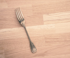 Silver fork lying on wooden table with copy space. Still life of vintage cutlery in kitchen. Concept of eating, cooking or restaurant.