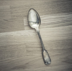 Silver spoon lying on wooden table. Still life of vintage cutlery in kitchen. Concept of eating, cooking or restaurant.