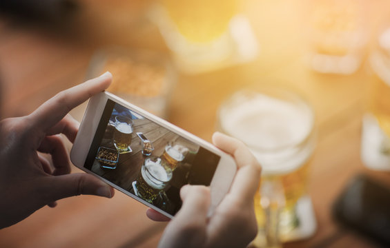 close up of hands with smartphone picturing beer