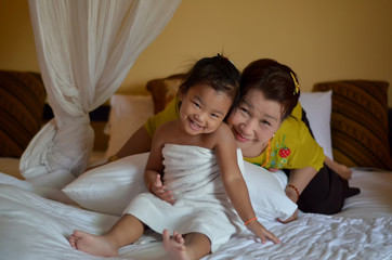 Grandmother and little cute daughter playing together in bed room,smile and happy in the morning.