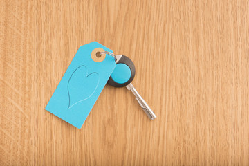 Modern key and blue label with heart symbol. Concept image of buying new property, love and romance or home security.