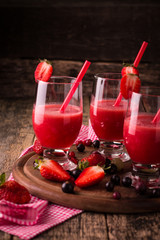 Glasses of fresh cold smoothie with fruit and berries, on wooden background, healthy detox drink