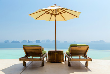 infinity pool with parasol and sun beds at seaside © Syda Productions