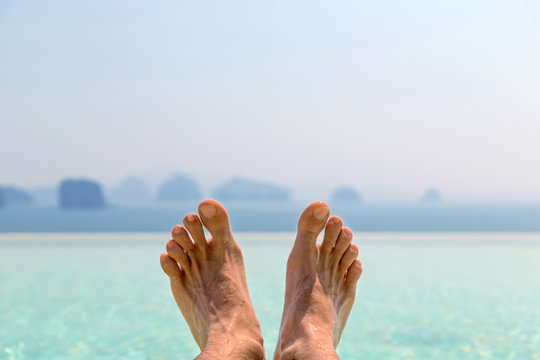 closeup of male feet over sea and sky on beach