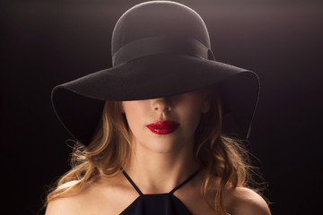 Fototapeta na wymiar beautiful woman in black hat over dark background
