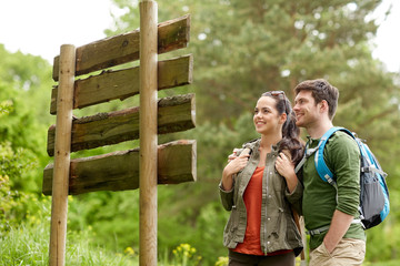 smiling couple at signpost with backpacks hiking © Syda Productions