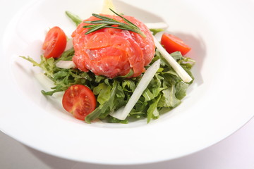 Red fish on Arugula in white plate