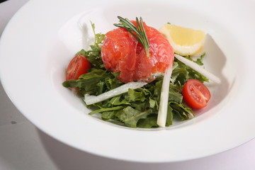 Red fish on Arugula in white plate