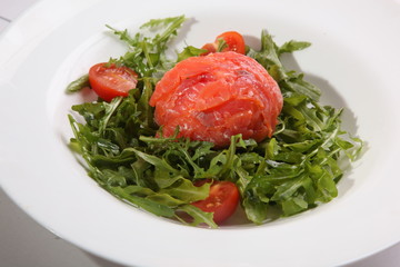 Red fish on Arugula in white plate