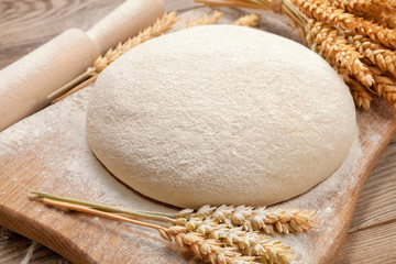 Fresh dough on a board with ears of wheat