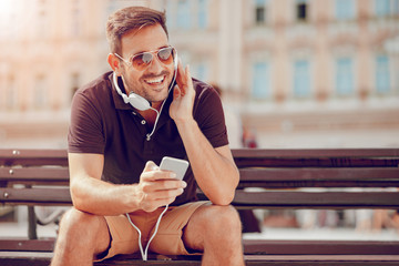 Young man listening music on smart phone in the city