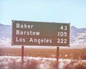 Obraz premium Znak drogowy w Kalifornii Los Angeles Baker Barstow. Znak autostrady w Kalifornii pokazujący przebieg do miast Baker, Barstow i Los Angeles. Nakręcony na pustyni Mohave wzdłuż autostrady międzystanowej nr 15.