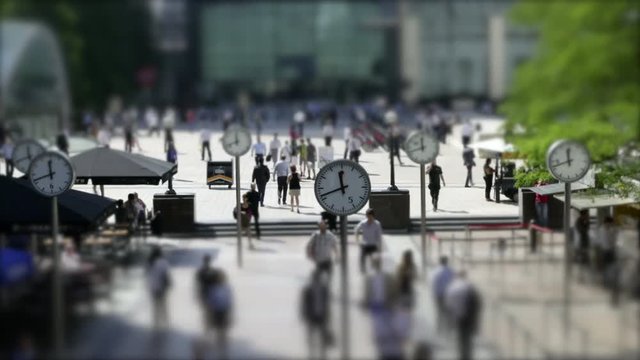 Time lapse of a busy business street with clocks in shallow focus on a bright sunny day